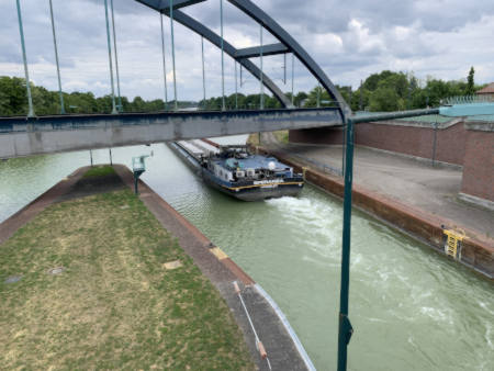 Münster/Westfalen Schleuse Binnenschiff fährt aus der Schleuse heraus. Die Schleuse befindet sich an der Dingstiege. Im Vordergrund sieht man die Eisenbahnbrücke der Linie Münster/Westfalen nach Osnabrück (Niedersachsen).