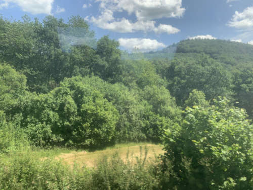 Fensterblick aus dem Zug auf die bergige Landschaft in Richtung Siegen Hauptbahnhof.
