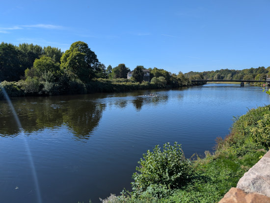 Fluss Ruhr bei Essen-Steele.
Flaches, ruhiges Wasser an einem blauem Himmel im Essener Osten mit warmen Wetter. T-Shirt und kurze Hose. Blickrichtung geht nach Westen zur Straßenbrücke nach Essen-Überrruhr.